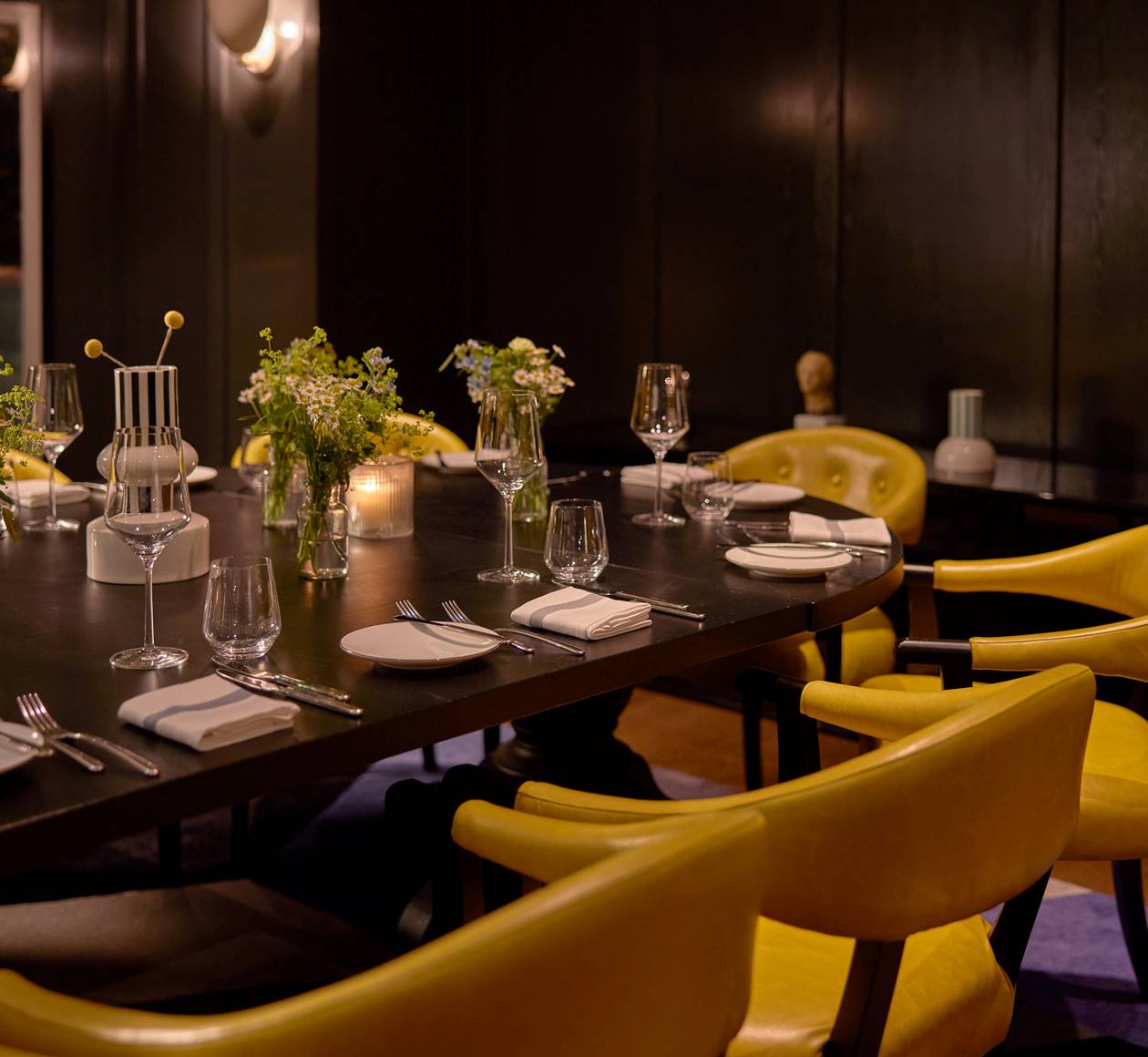 A person in denim clothes working on a laptop at a table with a coffee cup and muffin, in a stylish café setting at Celia.