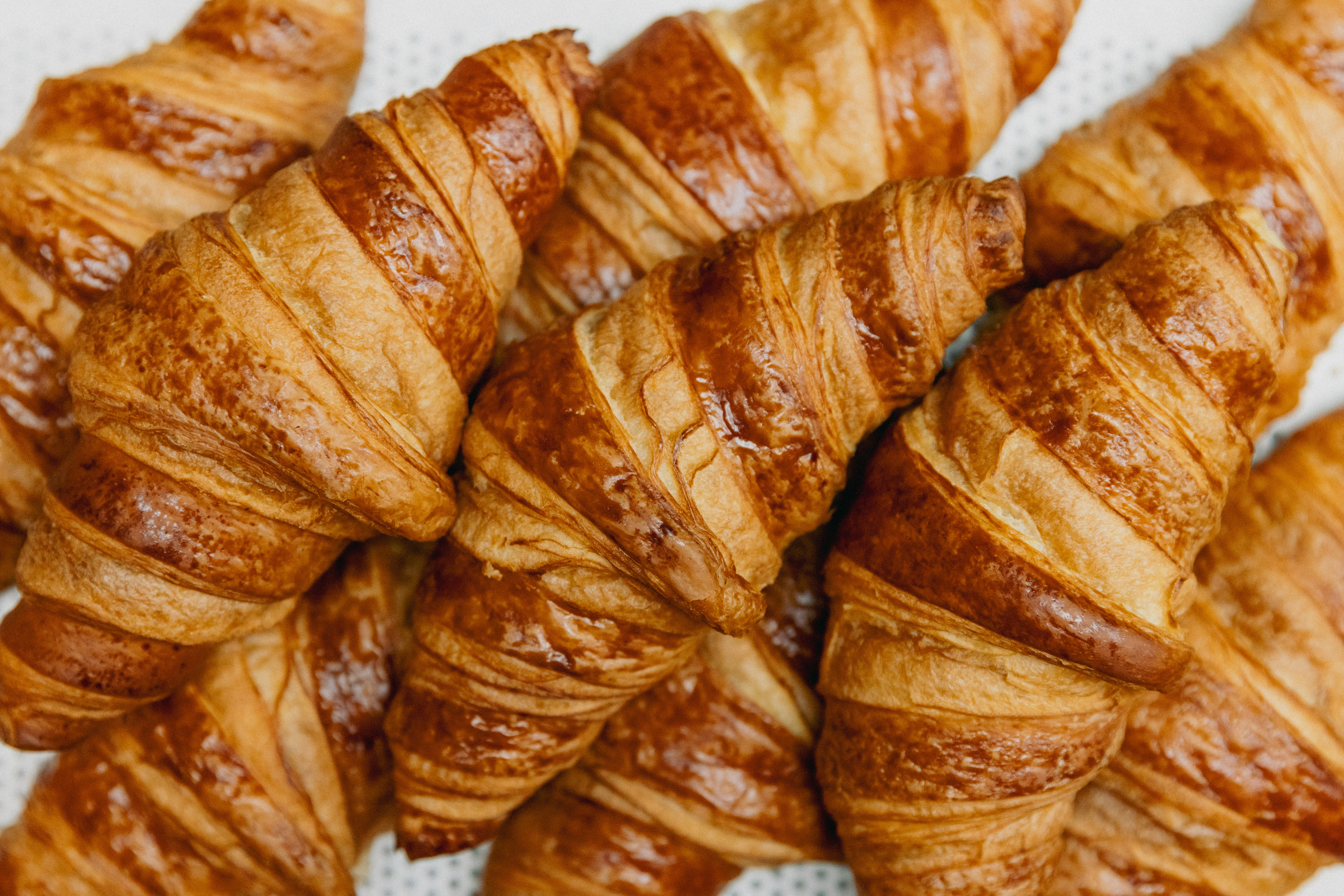 Freshly baked croissants arranged in a pile with golden, flaky layers for perfect Amsterdam breakfasts at Celia.