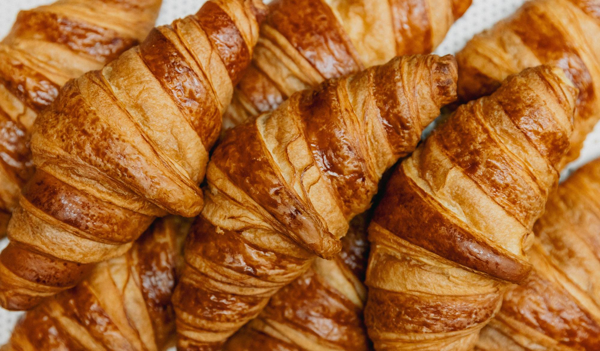 Freshly baked croissants arranged in a pile with golden, flaky layers for perfect Amsterdam breakfasts at Celia.