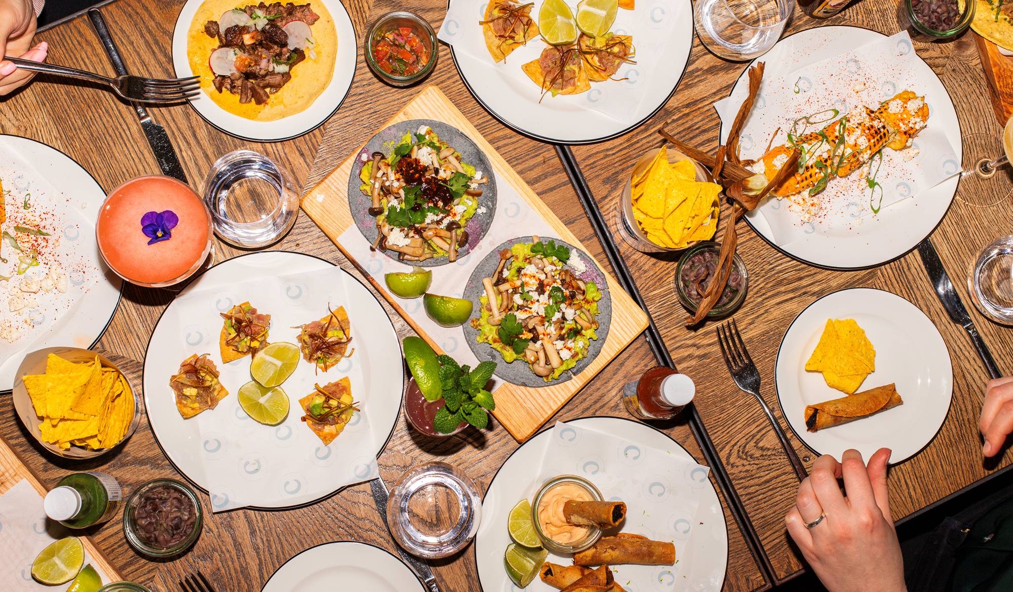 A table rich with food, featuring a roasted chicken, vegetables, and side dishes set for a boozy brunch at Celia Amsterdam.