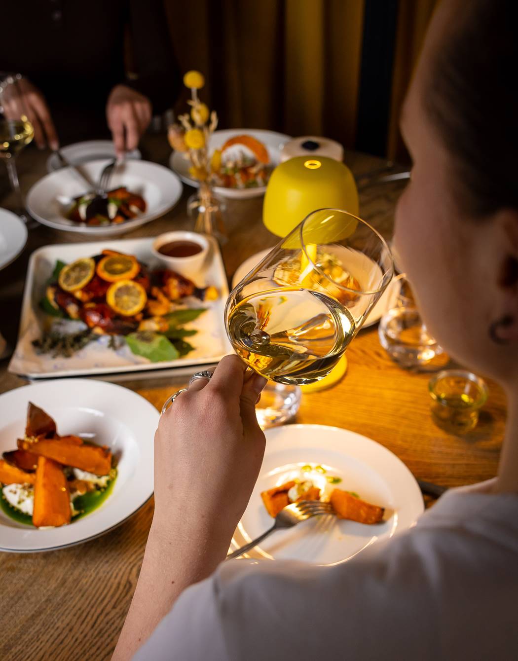 A person holding a wine glass over a table with various dishes at the relaxing Celia restaurant in Amsterdam.